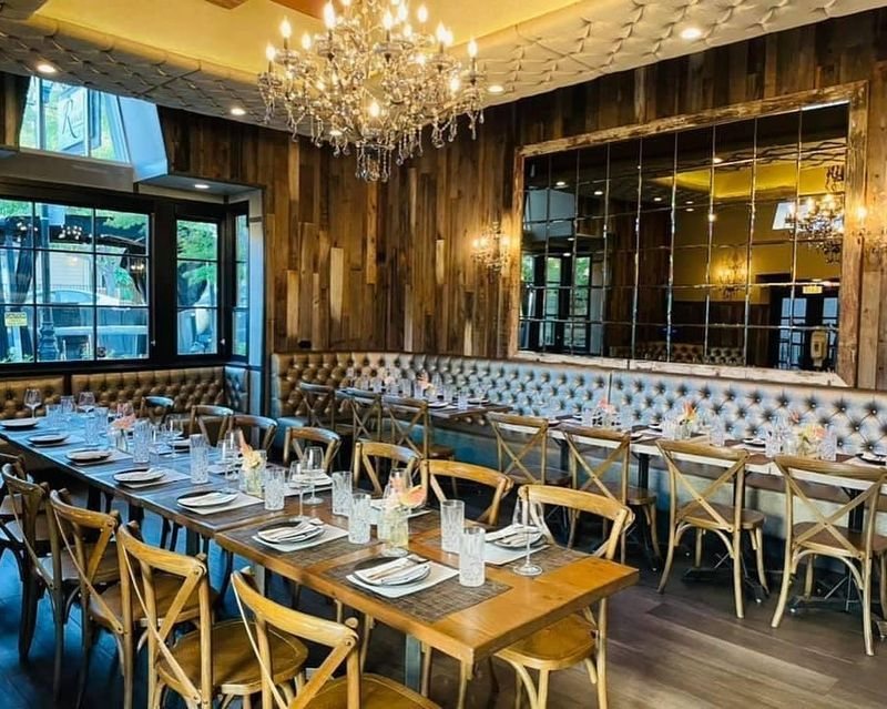 The dining room with reclaimed wood walls, tufted banquette and chandelier